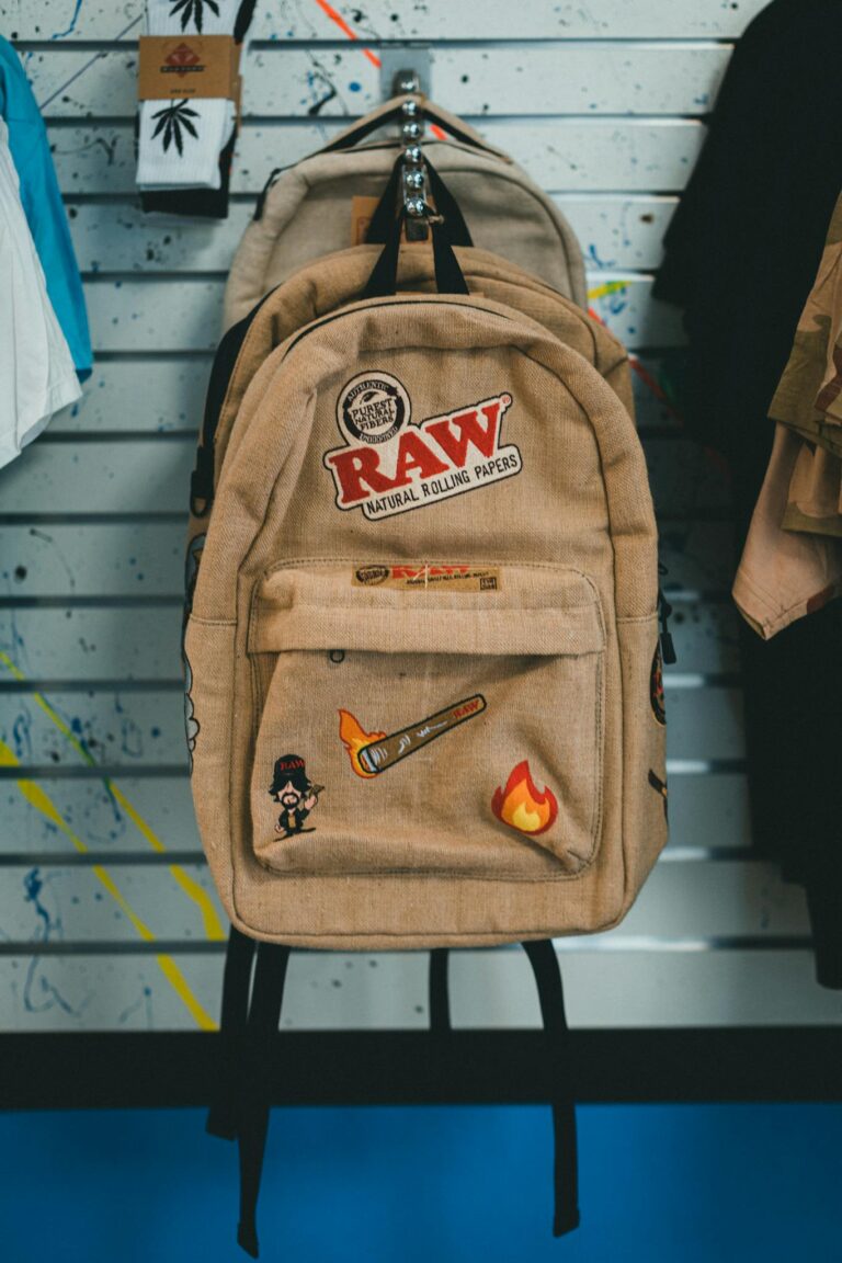 Beige backpack with artistic patches displayed in a store setting.