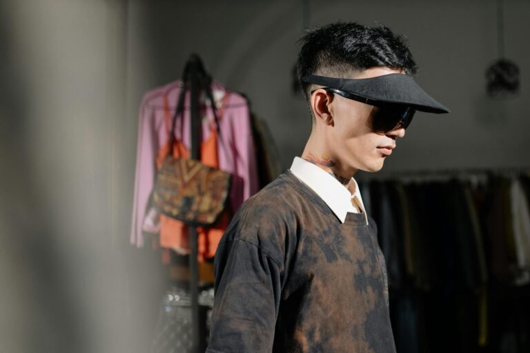 Fashion-forward man wearing a sun visor and sunglasses in a vintage clothing store.