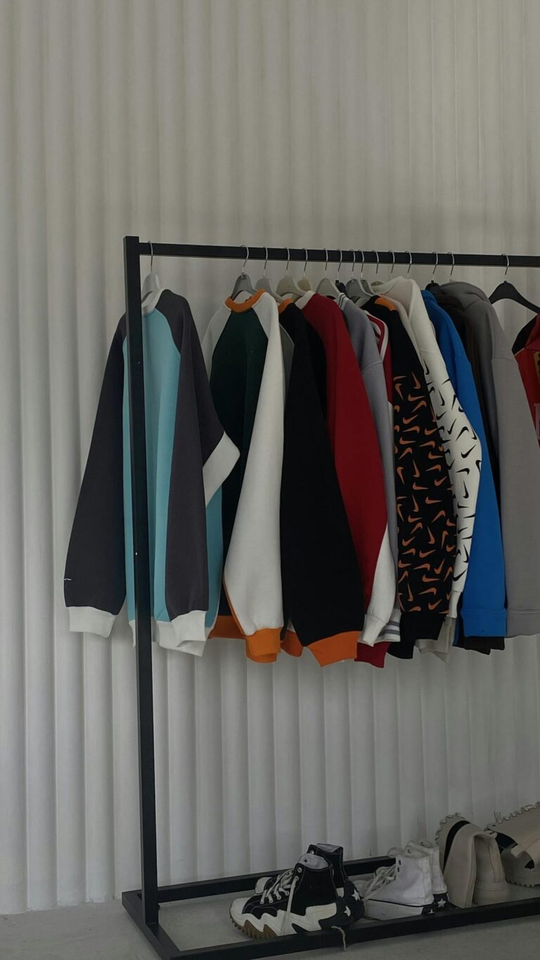 Minimalist rack displaying colorful sweatshirts against white backdrop in a trendy setting.